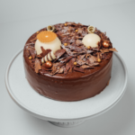 Chocolate cake with decorative toppings on a white cake stand.
