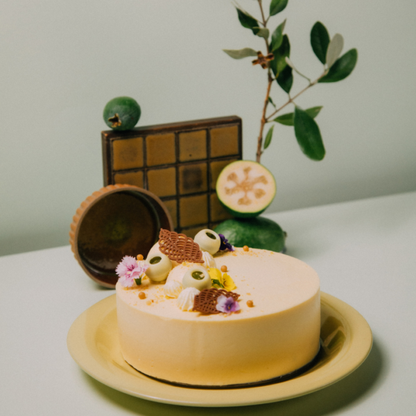 Decorative cake with flowers and fruit on a yellow plate.