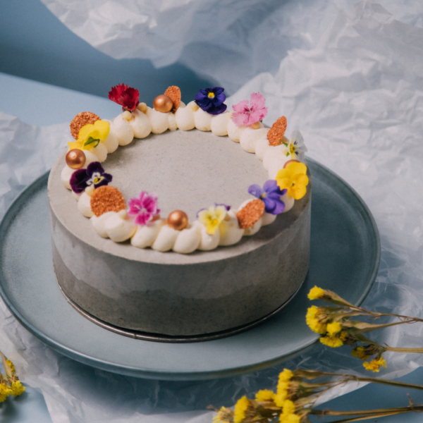 Cake with colorful flowers and decorations on a blue plate.