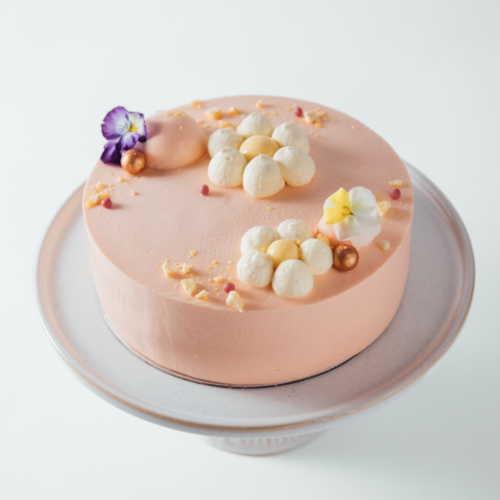 Elegant pink cake with floral decorations on a cake stand.