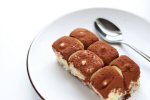 Tiramisu dessert on a white plate with a spoon.