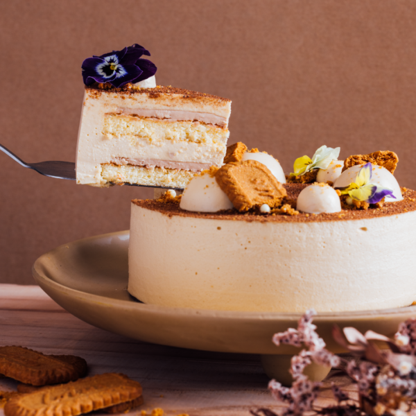 A slice of layered cake with flowers and cookies on top.