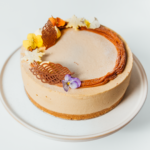 Creamy cake with floral and chocolate decorations on a white plate.