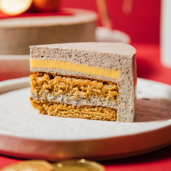Slice of layered cake on a white plate with red background.
