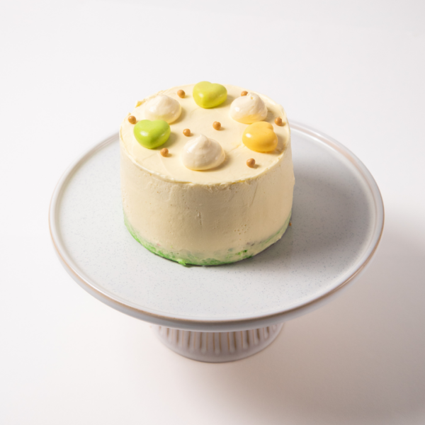 Pandan 1 Small frosted cake with colorful decorations on a white stand.