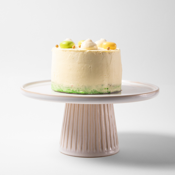 A decorated cake on a white pedestal stand.