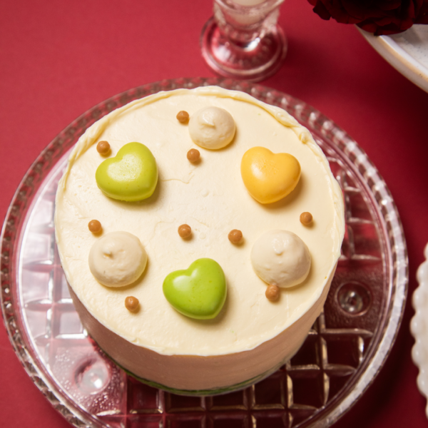 Round cake with heart-shaped decorations on a glass plate.
