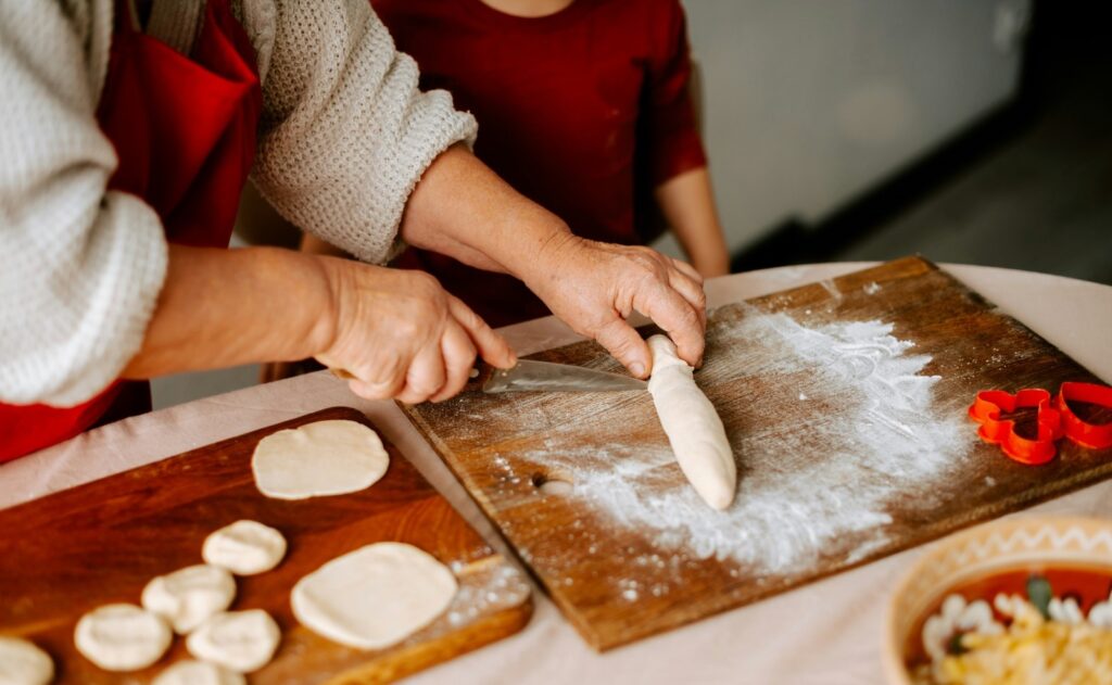 Person rolling dough on a floured board, preparing food.