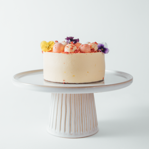 Elegant cake with flowers on a white stand.