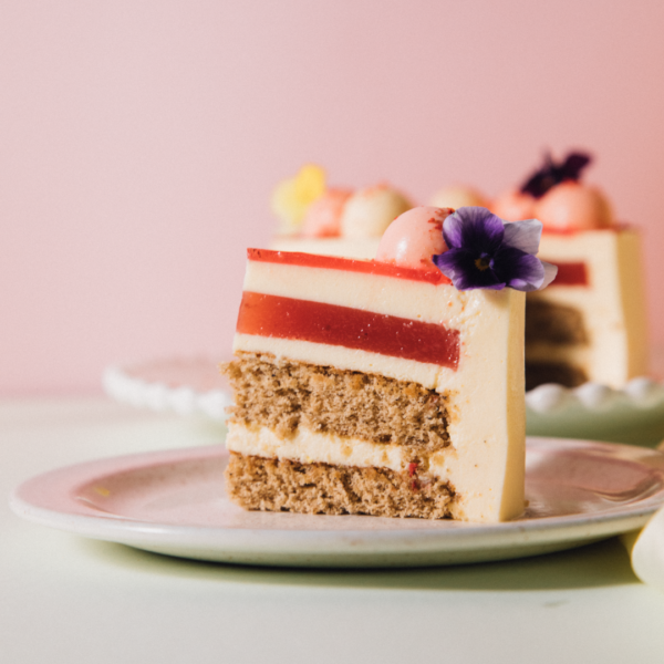 Slice of layered cake with flowers on a plate.